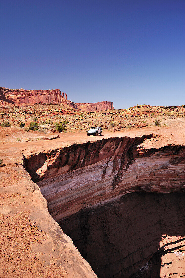 Jeep fährt an Felsabbruch über Colorado River entlang, White Rim Drive, White Rim Trail, Island in the Sky, Canyonlands Nationalpark, Moab, Utah, Südwesten, USA, Amerika