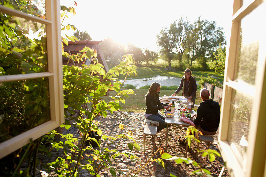 Leute sitzen im Garten und bereiten Abendessen vor, Haus Strauss, Bauernkate in Klein Thurow, Roggendorf, Mecklenburg-Vorpommern, Deutschland