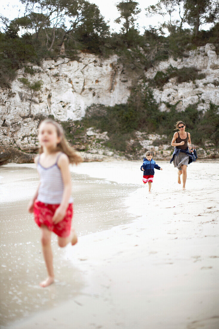 Frau und zwei Mädchen laufen am Strand entlang, Cala de s Almunia, Santanyi, Mallorca, Balearen, Spanien
