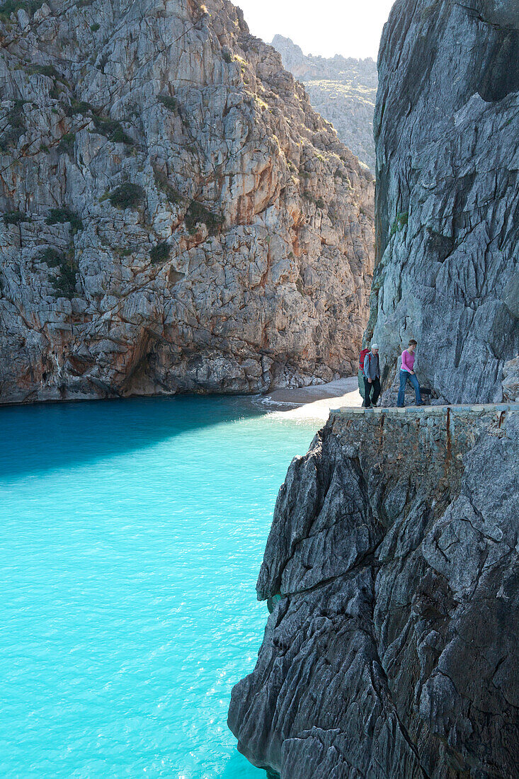 Wanderer auf Felspfad über Bucht von Sa Calobra, Cala de Sa Calobra, am Ende der Schlucht des Torrent de Pareis, romantischer Badestrand, Serra de Tramuntana, Unesco Weltkulturerbe, Mallorca, Spanien