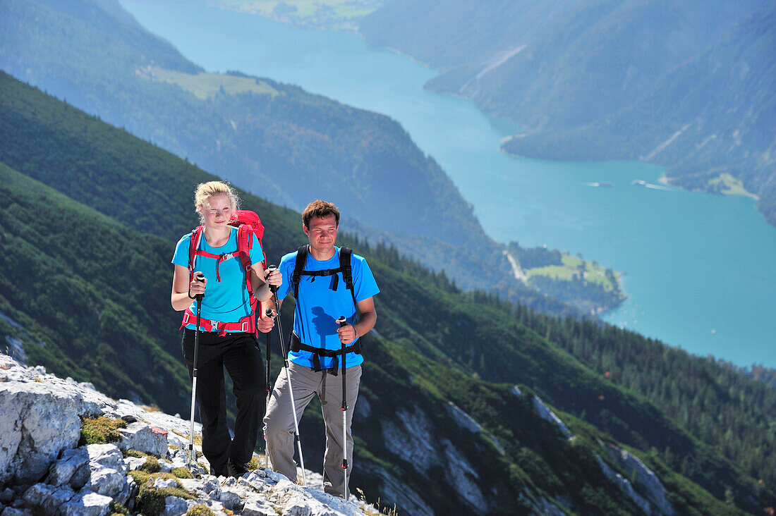 Young woman and young man hiking on ridge, Lake Achen in background, Unnutz, Brandenberg Alps, Tyrol, Austria