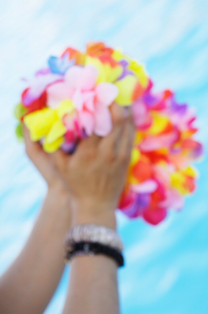 Close-up of a woman's hand holding  necklaces of flowers