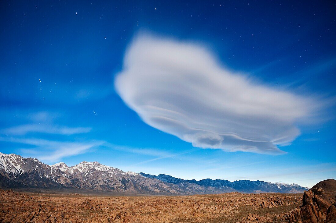 Ghostly lenticular cloud illuminated by full moon over Alabama Hills and Sierra Nevada mountains, California, USA