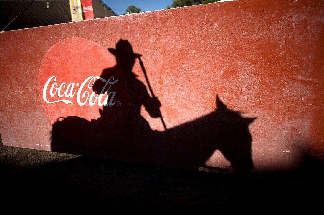 The shadow of a picador on his horse is cast on a door with a Coca-Cola logo before a bullfight in Tlaxcala, Mexico.