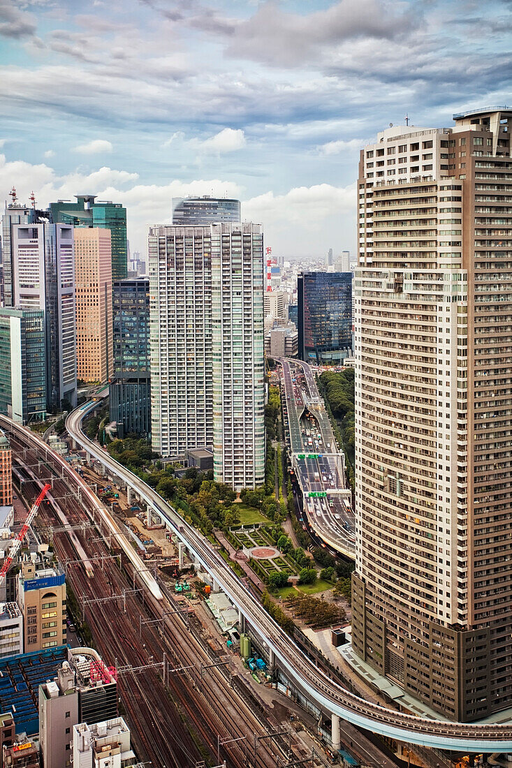 Downtown Tokyo skyline viewed from above. Densely populated and built up area of the city. Elevated roadway with traffic. Railway tracks and public transport. City infrastructure. Cars with lights on. Dusk., Tokyo city skyline, Japan