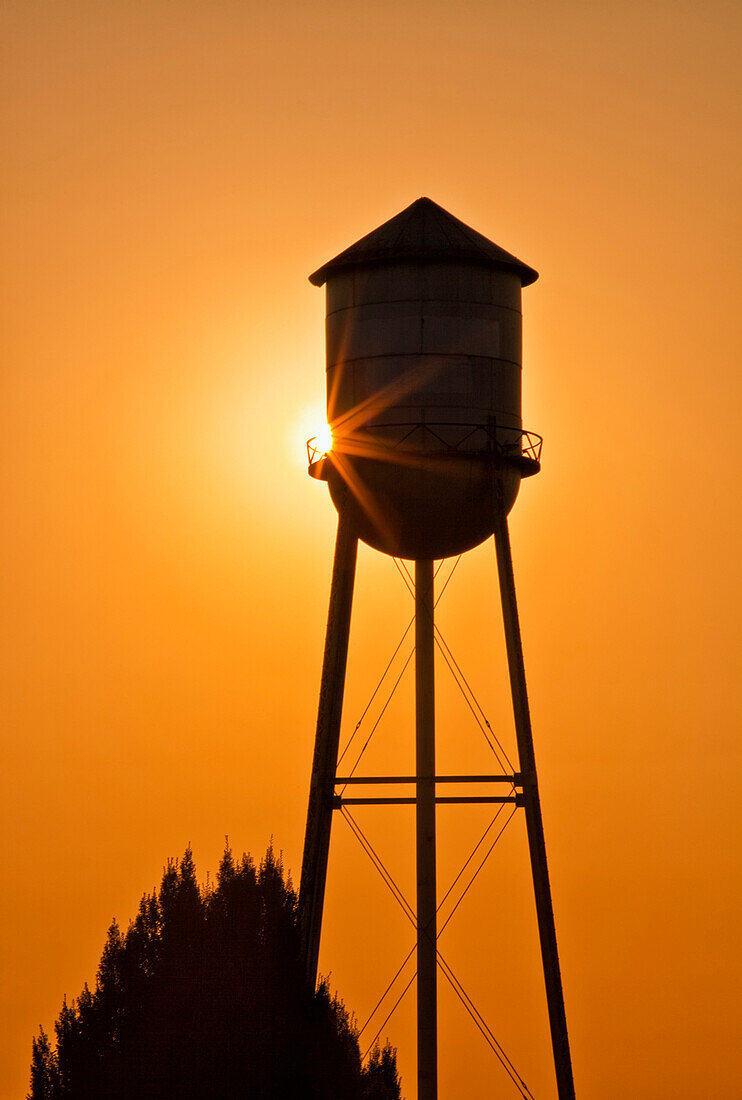 Sun setting behind agricultural water tower, Willamette Valley, Oregon, USA, Sunset and an agricultural water storage tower
