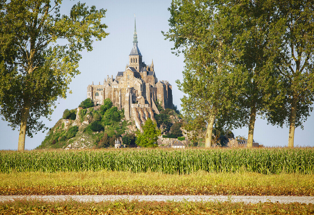 A view of Le Mont Saint-Michel. Historic monument and UNESCO world heritage site on a rocky outcrop on the mud flats off the coast of Normandy. A cathedral with a tall spire. An international landmark. Farmland onthe coast., Le Mont Saint-Michel, Normandy