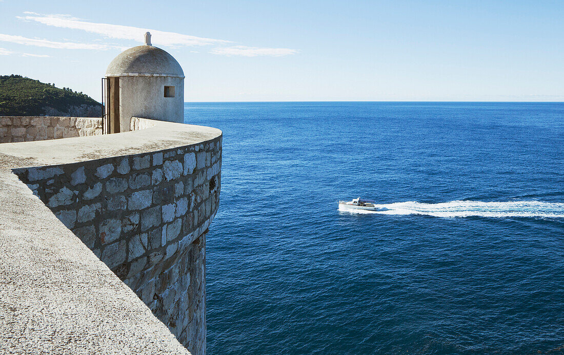 An outpost overlooking the Adriatic Sea on the old city wall in Dubrovnik. A Unesco world heritage site. A motorboat on the water., Dubrovnik, Croatia
