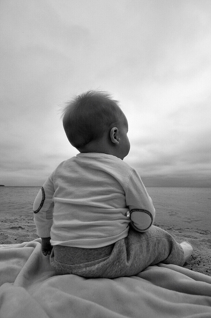 Baby Boy Sitting on Beach, Rear View