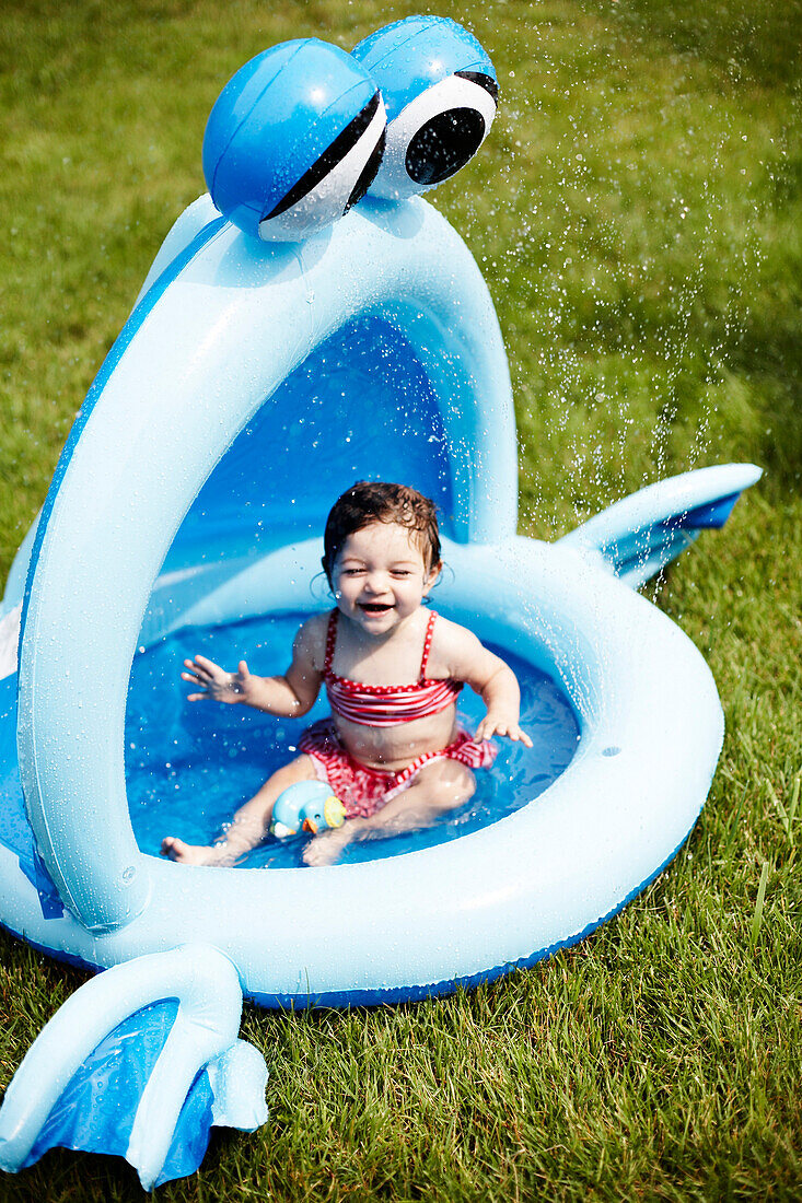 Young Girl in Red Bathing Suit Sitting in Small Pool