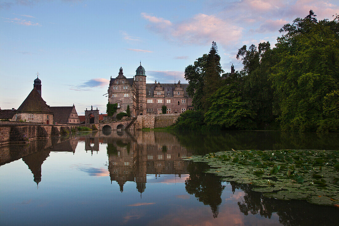 View over the pond onto Haemelschenburg castle at dusk, Emmerthal, Weser Hills, North Lower Saxony, Germany, Europe