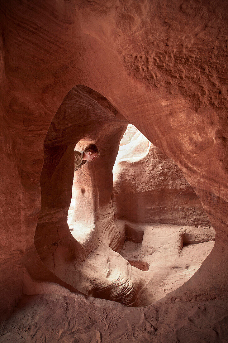 Archaeology student looking into cave tomb in Petra, UNESCO world heritage, Wadi Musa, Jordan, Middle East, Asia