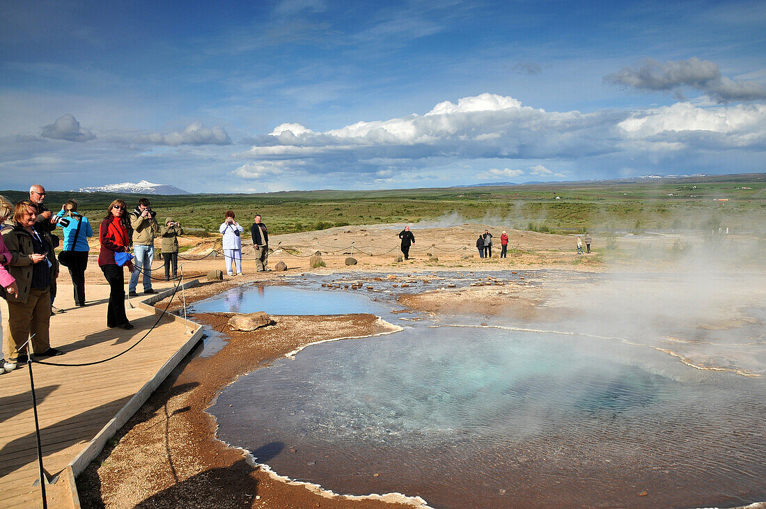 Tourists at one geyser hole in the valley of Haukadalur at the golden circle, Iceland, Europe