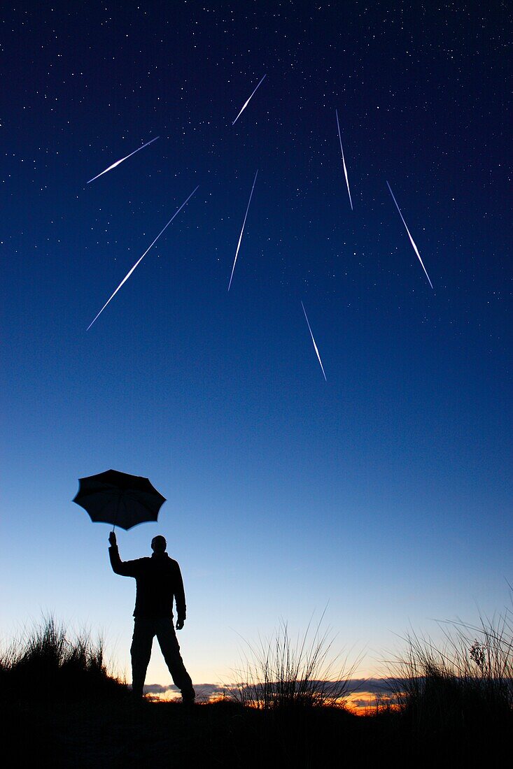 Figure of a man holding an umbrella during shooting stars