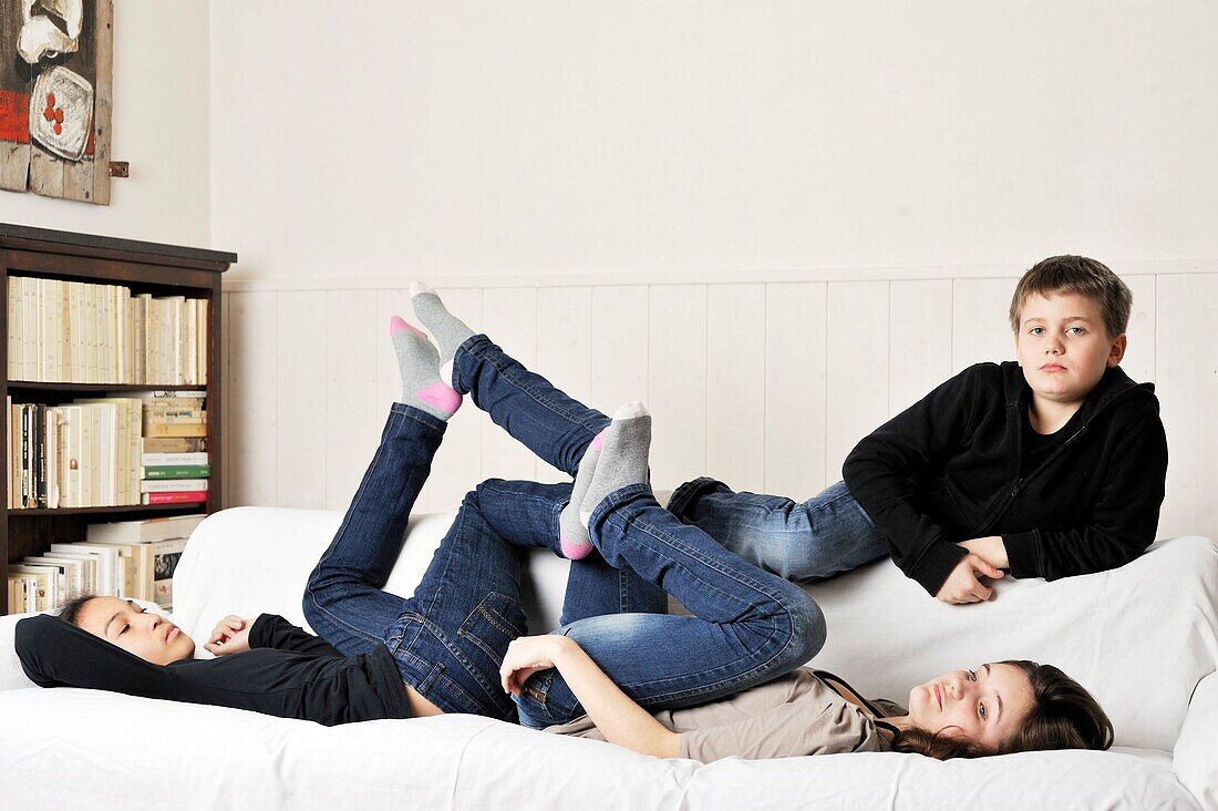 3 young teens boring on a sofa