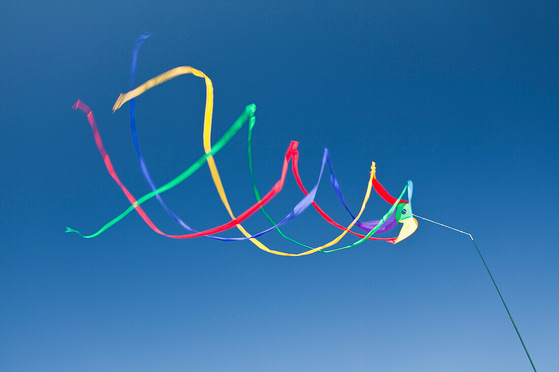 Wind streamers spinning in breeze. Narrow strips of coloured material, creating a pattern. Pole. Blue sky.  Long Beach, Washington, USA. Circular patterns., Wind streamers waving in the air