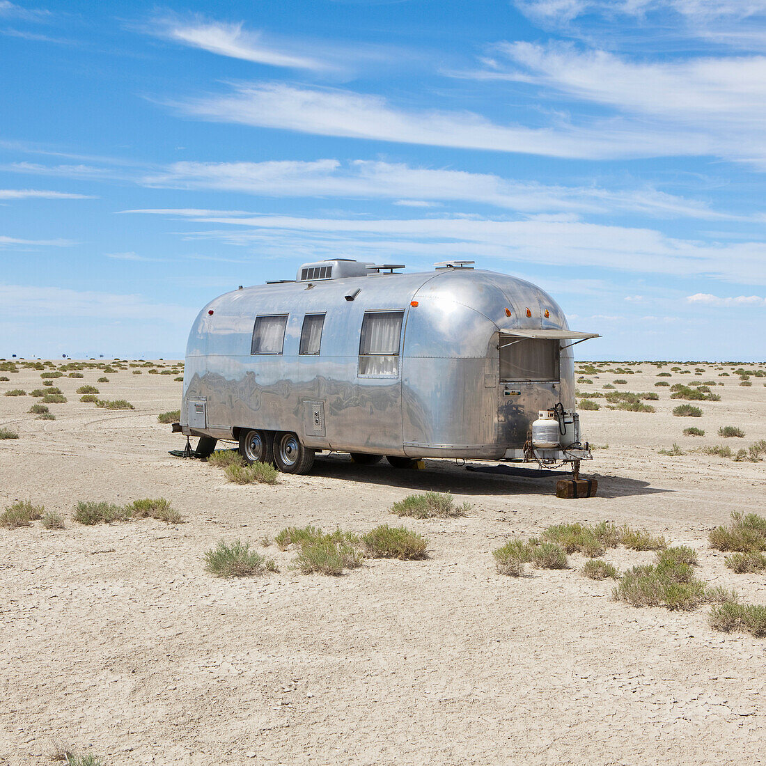 Vintage Airstream trailer on Bonneville Salt Flats, photographed during Speed Week, an annual amateur auto racing event in Utah, USA. Caravan, silver exterior., Vintage Airstream trailer in desert