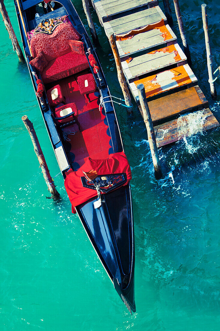 An empty gondola docked at a worn out pier in the city of Venice, Italy., Venice, Italy / Gondola