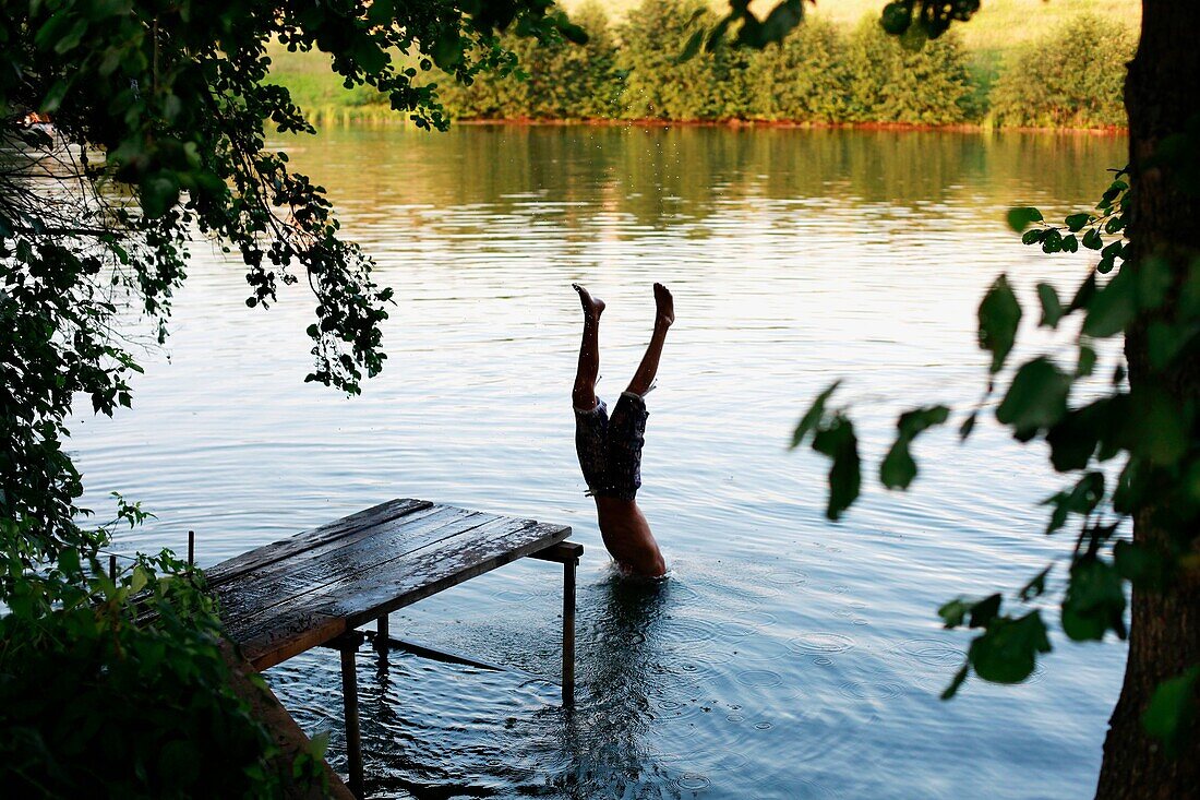 Boy jump from the pier in Lake Avral, Kirillovka, Samara Region, Russian Federation
