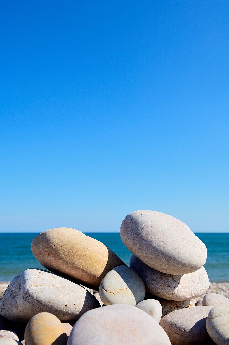 Pebbles stacked on a beach under a clear blue sky