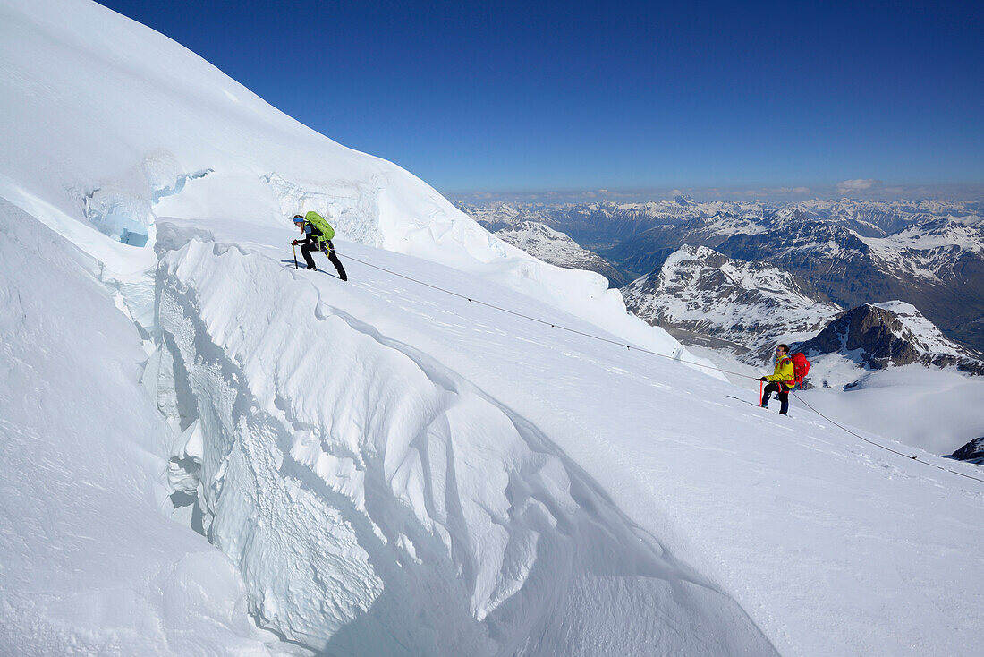 Two mountaineers traversing big crevasse, Piz Palue, Grisons, Switzerland