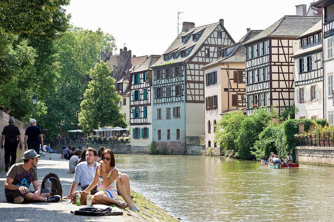 People sitting along the bank of the river, Petite France quarter, Strasbourg, Alsace, France