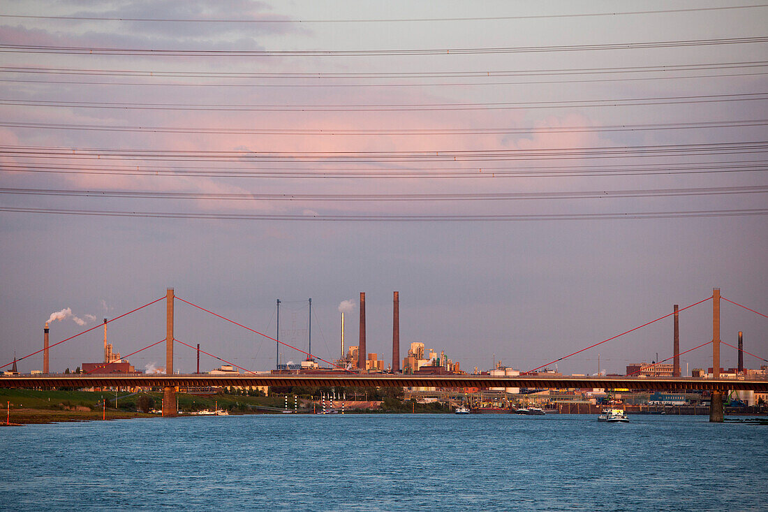 Stromleitungen, Brücke über Rhein, Fabrik und Schornsteine vom Bayer Werk in der Abenddämmerung, Leverkusen, Nordrhein-Westfalen, Deutschland, Europa