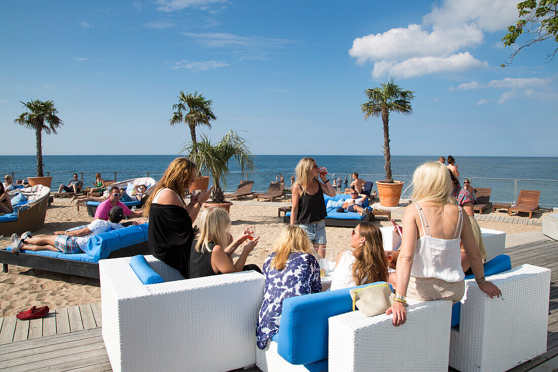 Young women relaxing on lounge chairs at the trendy Kallis Beach Club, Visby, Gotland, Sweden, Europe