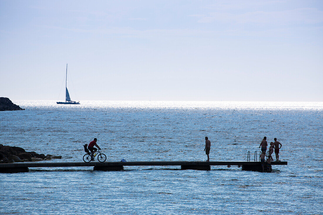Silhouette von Segelboot, Fahrrad und Menschen auf einem Steg, Visby, Gotland, Schweden, Europa