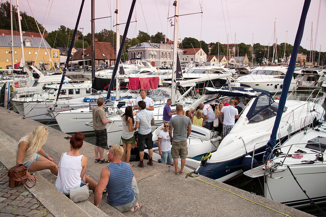 Menschen feiern an Bord einer Jacht im Jachthafen, Visby, Gotland, Schweden, Europa