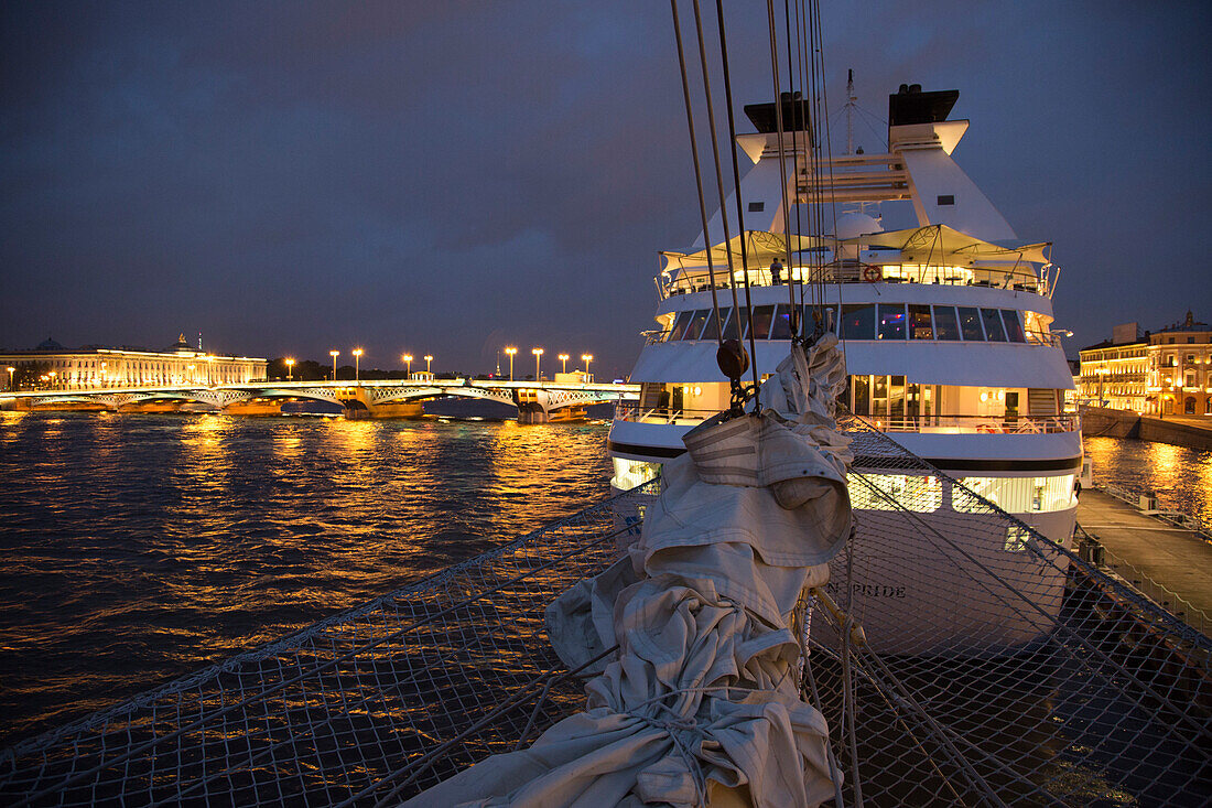 Bowsprit of sailing cruise ship Star Flyer and cruise ship Seabourn Pride docked on Neva river at night, St. Petersburg, Russia, Europe