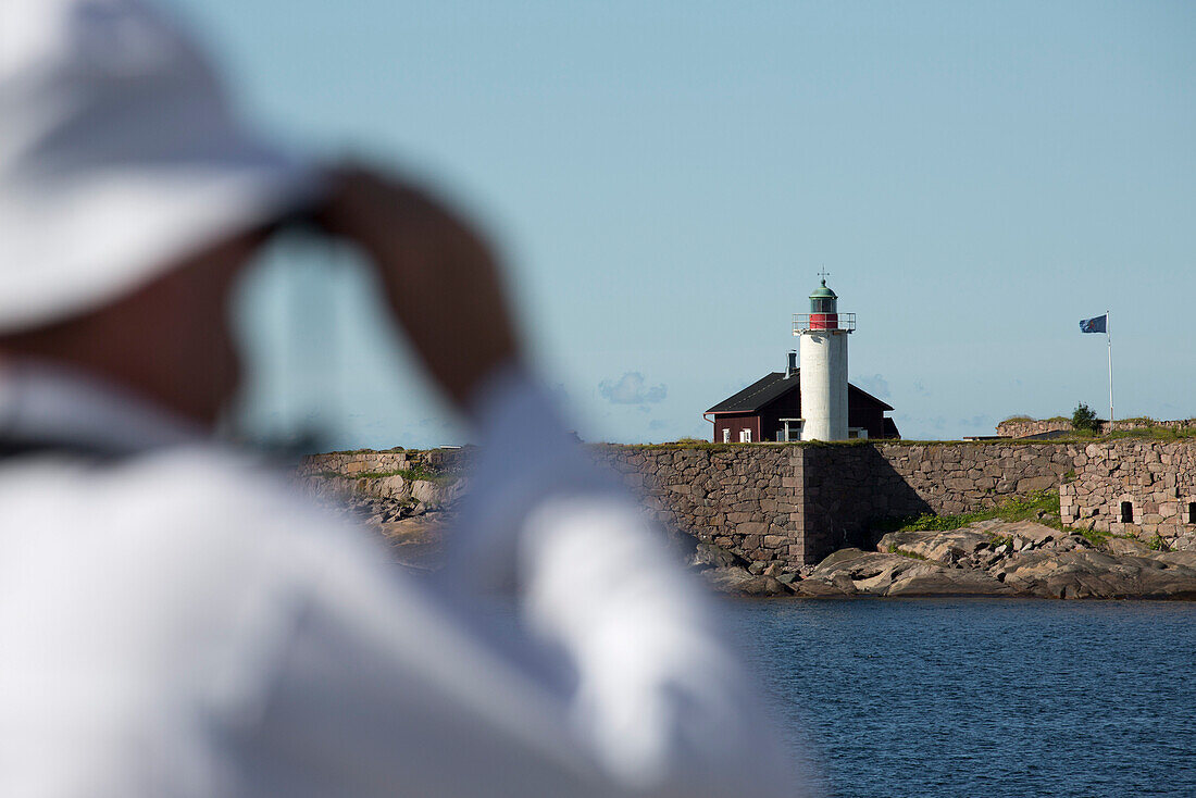 Man with binoculars looking from sailing cruise ship Star Flyer at a lighthouse, Hanko, Southern Finland, Finland, Europe