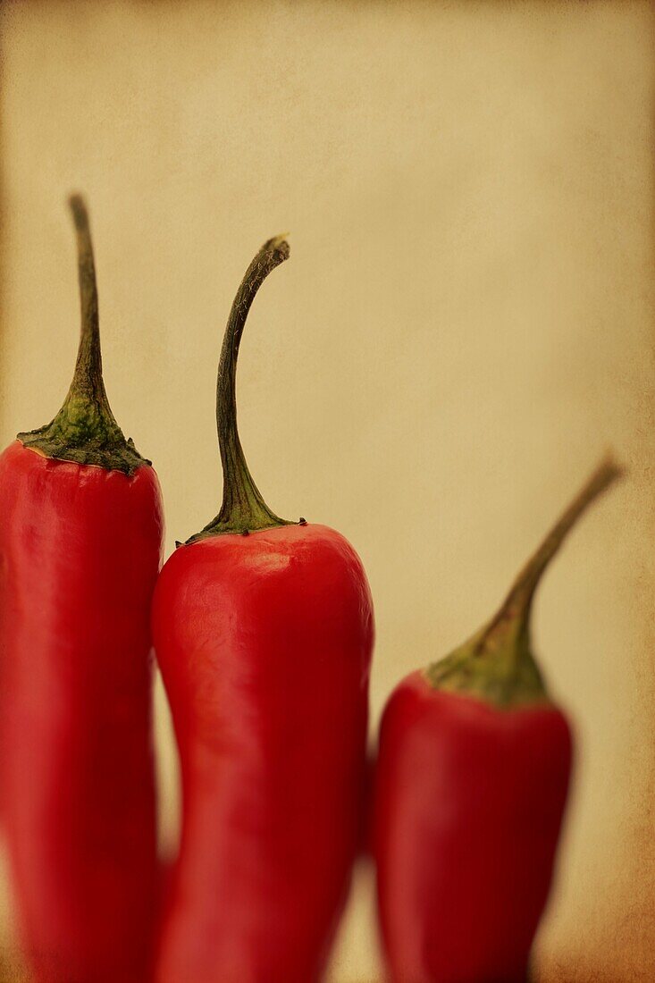 Three red chillis close up with a textured finish.