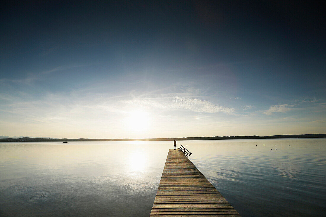 Woman standing on a jetty at lake Starnberg, Upper Bavaria, Germany