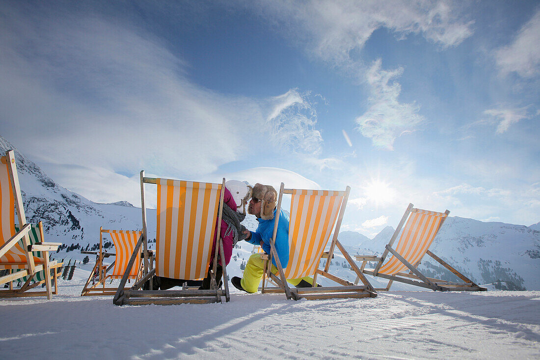 Couple sitting in deck chairs in snow, Kuehtai, Tyrol, Austria