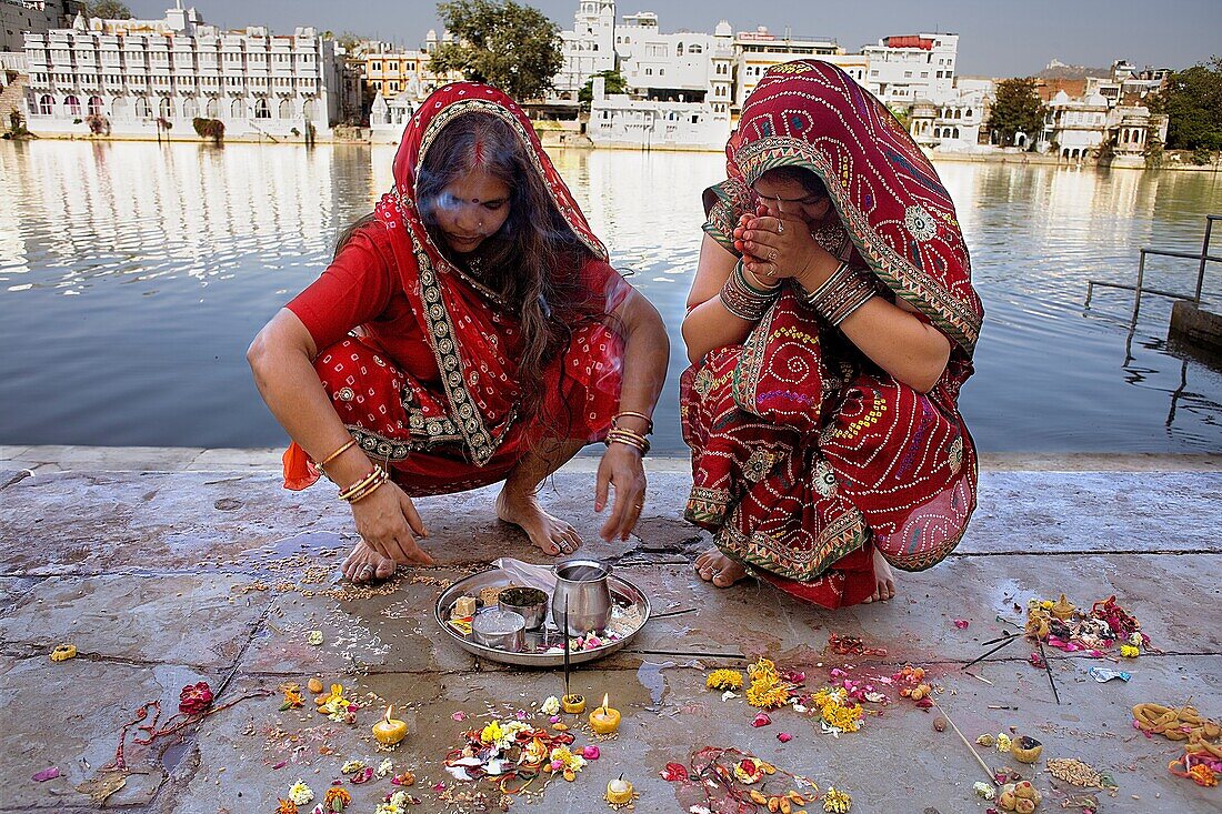 Girls praying, making a offering,in Gangaur ghat,Pichola lake,Udaipur, Rajasthan, india