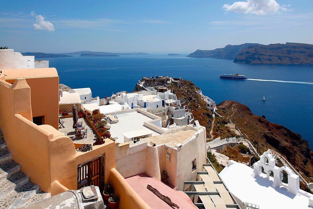 View above terraces overlooking caldera and ferry in the village of Oia in Santorini, Greece