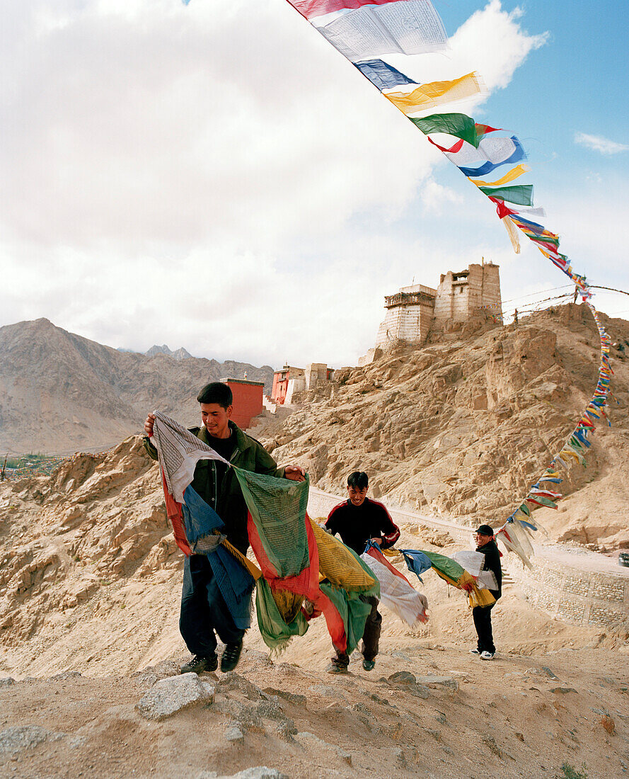 Men with buddhist prayer flags over capital Leh, Indus valley, Ladakh, Jammu and Kashmir, India