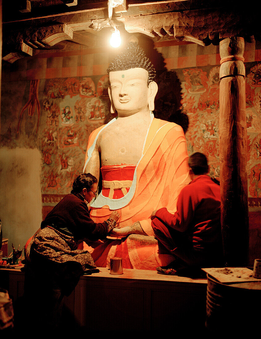 Restorers painting buddha statue in prayers room of convent Tiksey Gonpa, southeast of Leh, Ladakh, Jammu and Kashmir, India