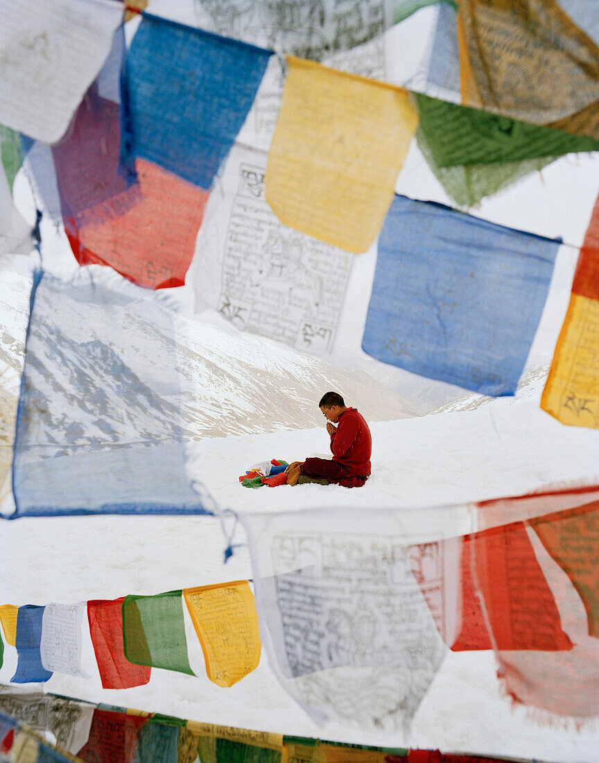 Mönch Wangyal betet auf Khardung La, weiht Gebetsfahnen, 5570 m, höchster befahrbarer Pass und höchste Straße der Welt, nördlich vom Leh, Ladakh, Jammu und Kashmir, Indien