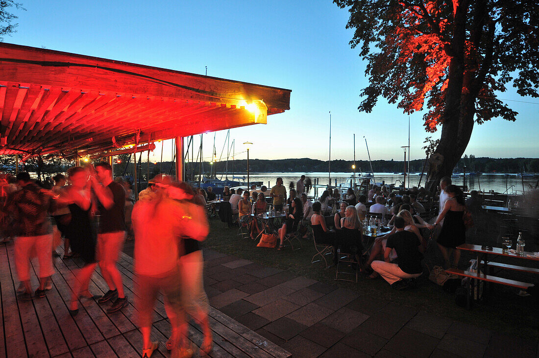 Menschen tanzen am Ufer des Ammersees bei Sonnenuntergang, Herrsching, Oberbayern, Bayern,  Deutschland, Europa