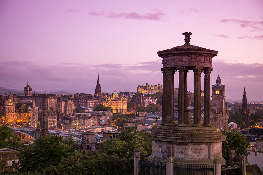 Dugald Stewart Monument on Calton Hill with Edinburgh Castle and cityscape at dusk, Edinburgh, Scotland, United Kingdom
