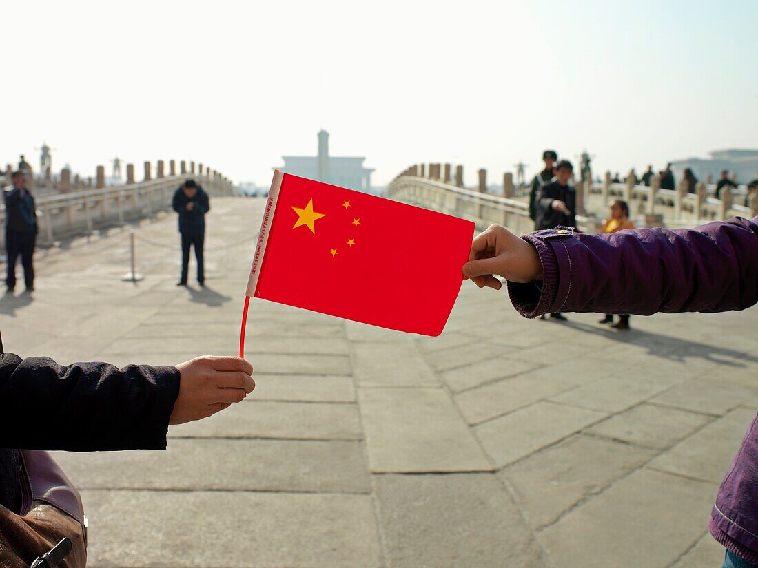 A visitor to the Forbidden City in Beijing, China, holds a Chinese flag
