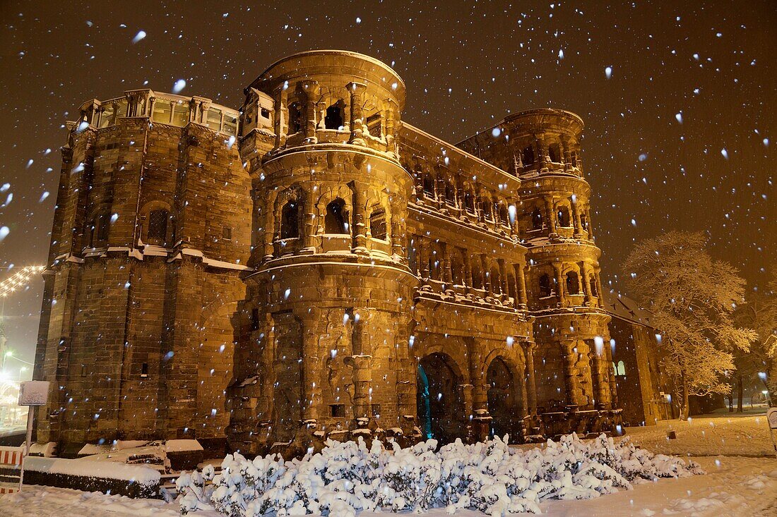 Porta Nigra with snowfall, World Heritage Site, illuminated at night, Trier, Germany