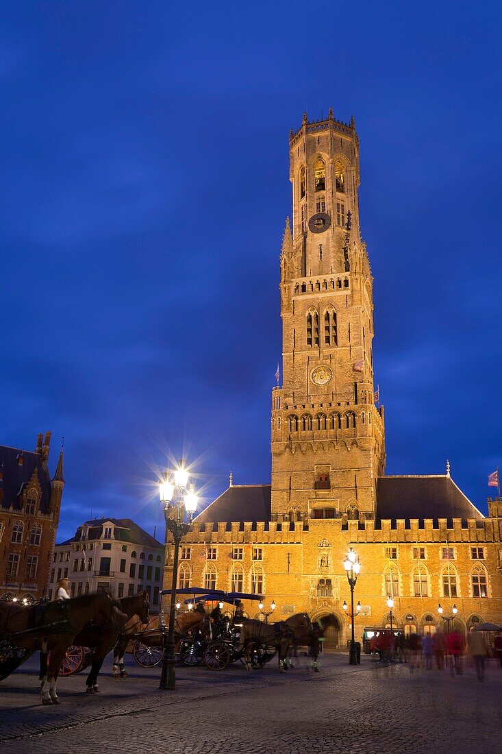 belfry and horse-drawn carriages, illuminated at night, Bruges, Belgium
