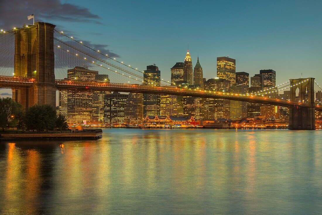 Brooklyn Bridge, East River, South Street Seaport, and lower Manhattan skyline at dusk, as seen from Brooklyn Bridge Park, New York City, New York, USA