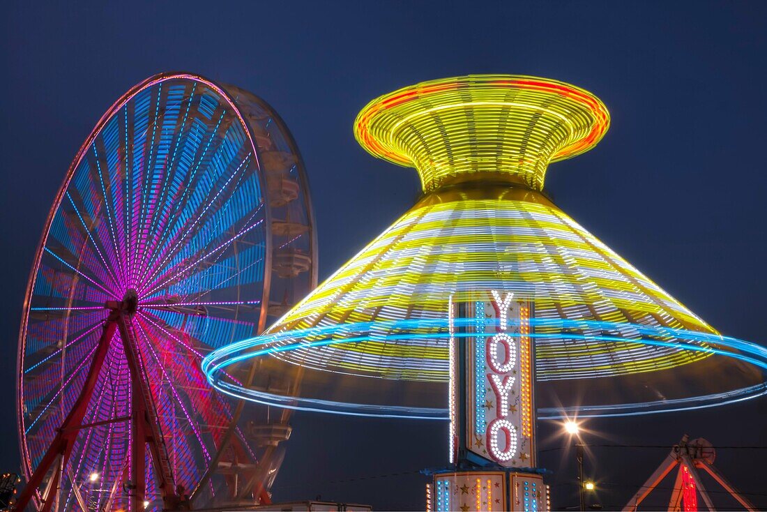 AUGUSTA, NJ - AUGUST 13: The colorfully illuminated Yo Yo spins in front of the Gentle Giant Ferris Wheel against the night sky during the New Jersey State Fair on August 13, 2010 at the Sussex County Fairgrounds, Augusta, New Jersey