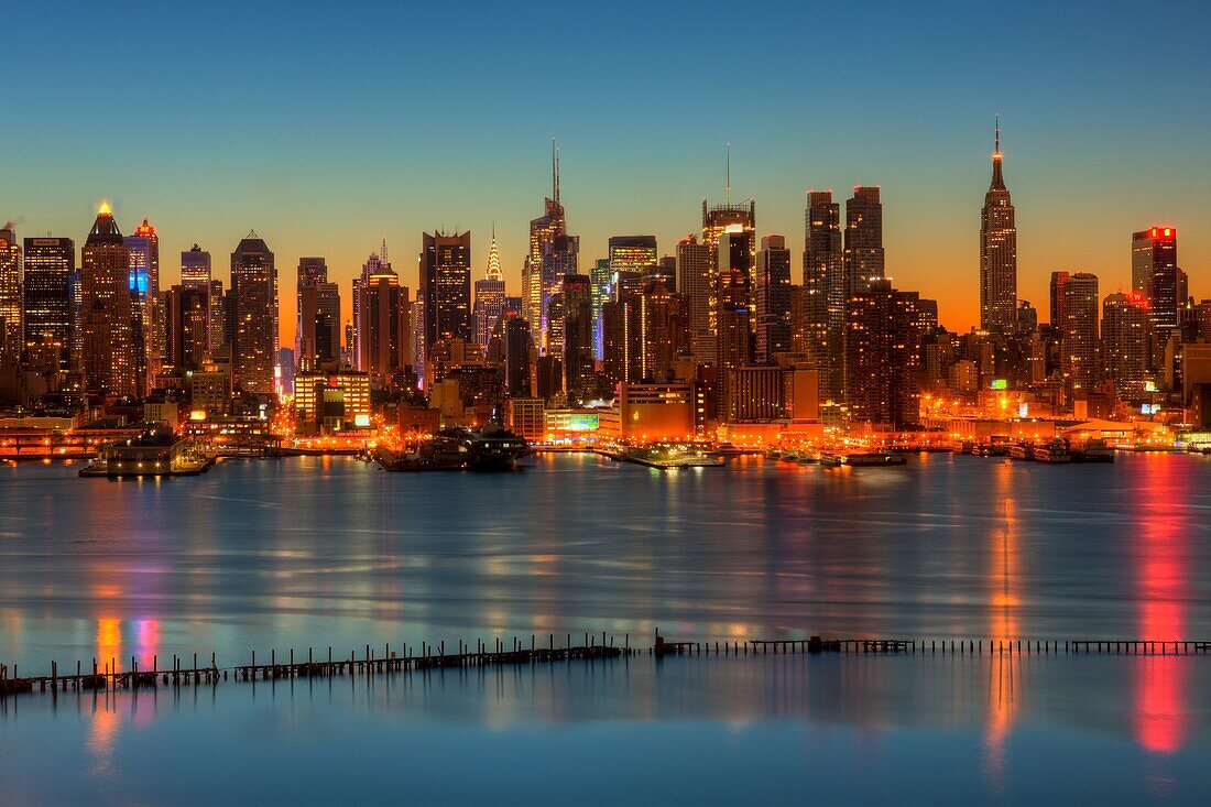 The Manhattan skyline in New York City during morning twilight as viewed over the Hudson River looking east from New Jersey. The cool blue eastern sky was accented with tinges of orange that began to show in the hour before sunrise.
