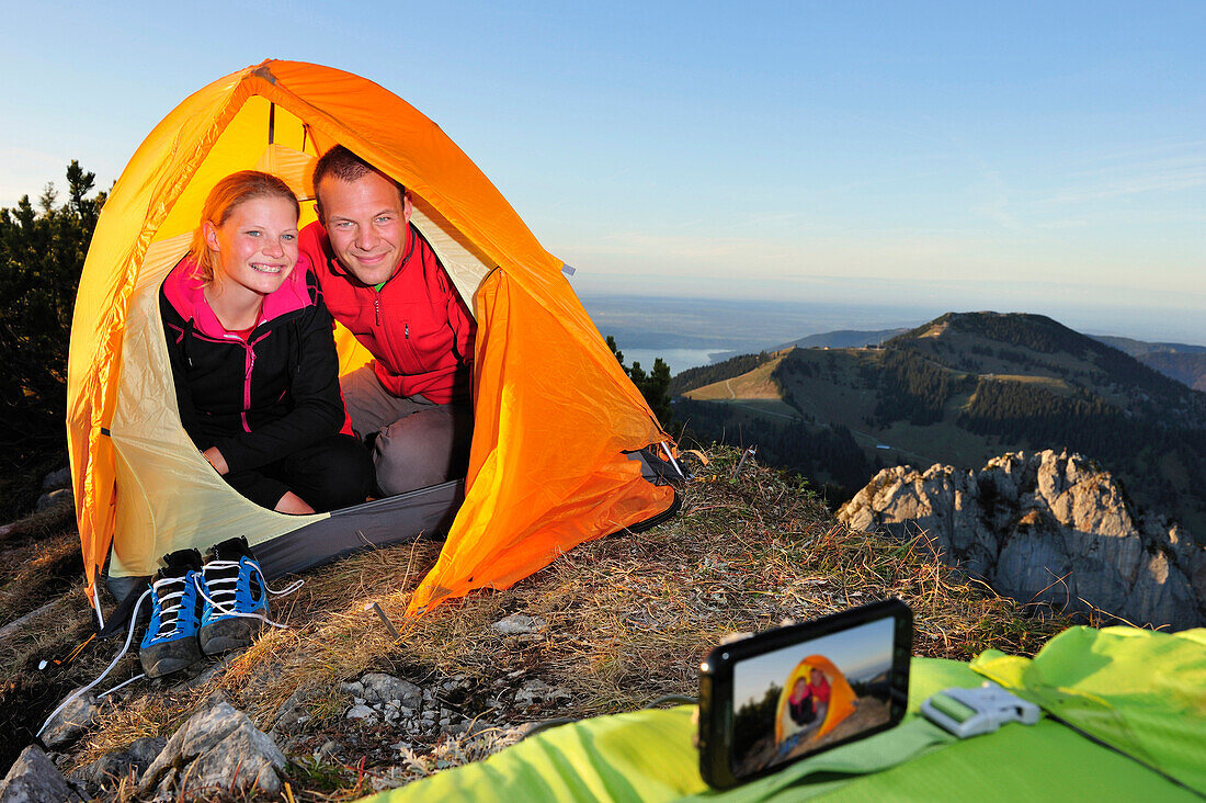 Couple in a tent taking pictures of themselves with a mobile phone, Risserkogel, Bavarian Prealps, Mangfall Mountains, Bavaria, Germany