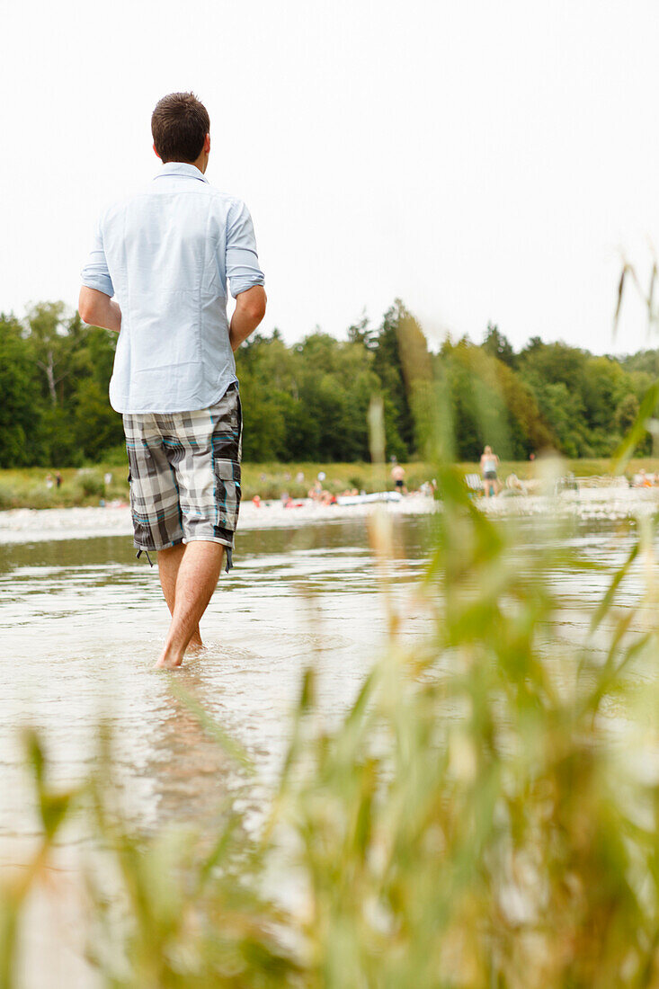 Junger Mann steht in der Isar, München, Bayern, Deutschland